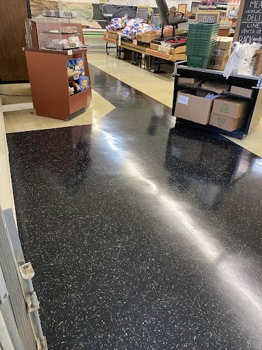 A grocery store with a black floor and a wooden counter.