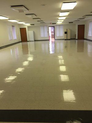 A large empty room with a shiny floor and lots of windows.
