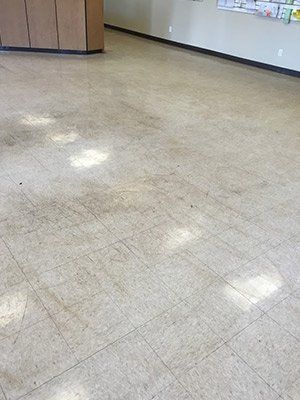 A large empty room with a tiled floor and a wall.