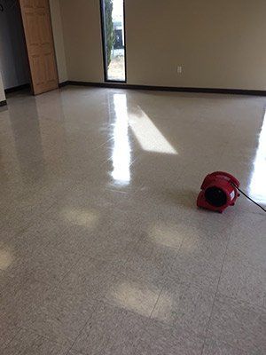 A red fan is sitting on the floor of an empty room.
