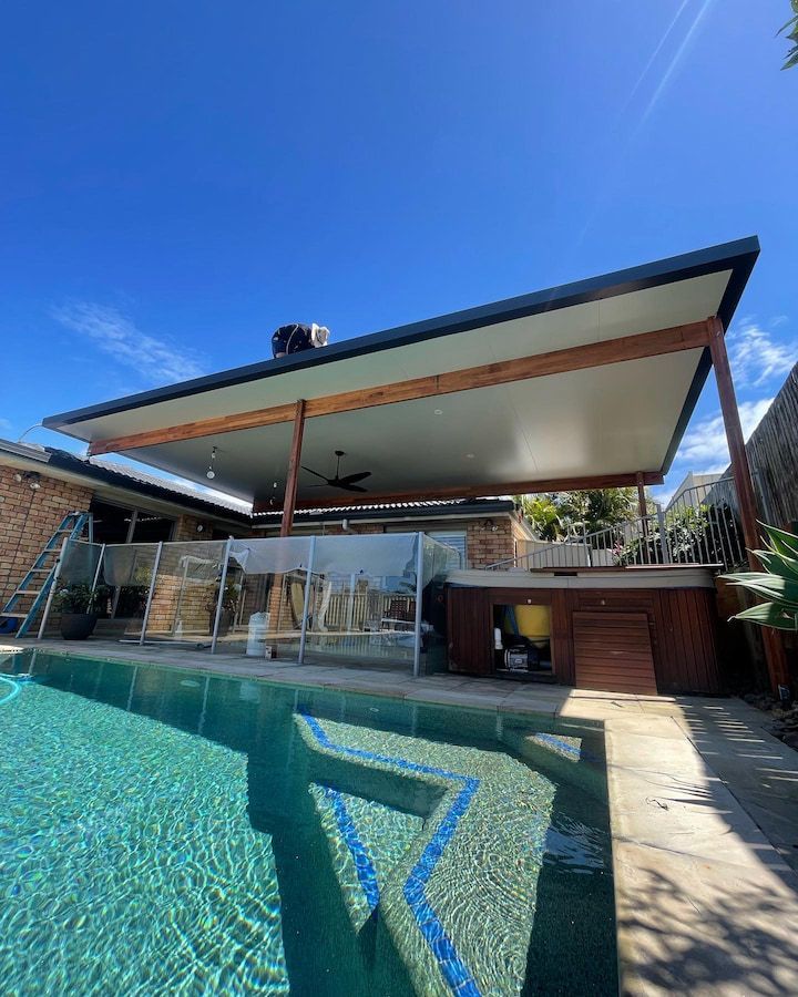 There is a swimming pool in the backyard of a house under a Gold Coast patio