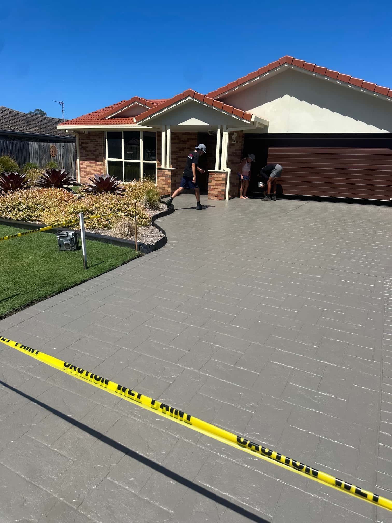 A man is walking down a concrete driveway in front of a house.
