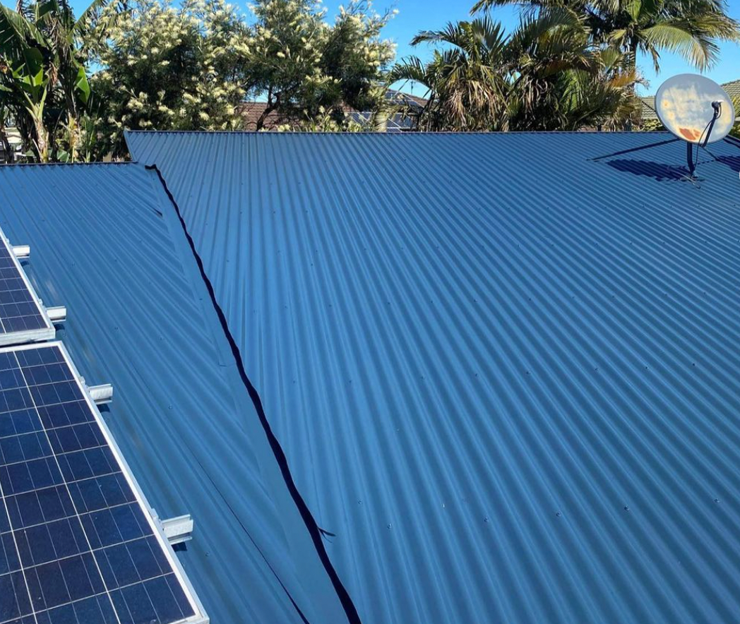 A blue roof with solar panels and a satellite dish on it.