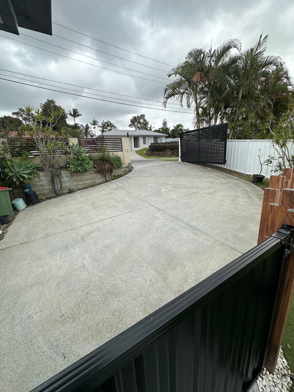 A pressure cleaned driveway leading to a house with a black gate.