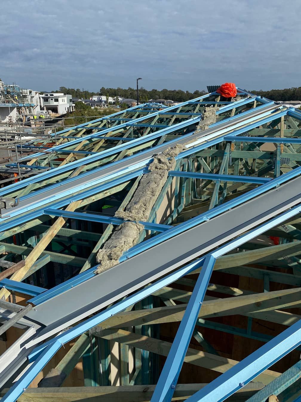 The roof of a building is being built and a man is standing on top of it.