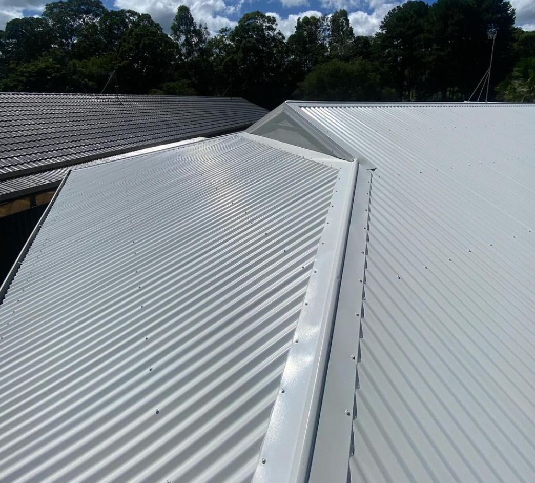 A white corrugated metal roof with trees in the background.