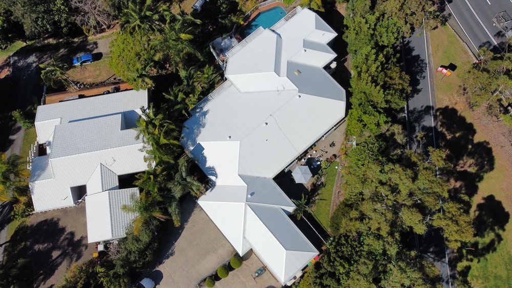 An aerial view of a large white roof surrounded by trees and a road.
