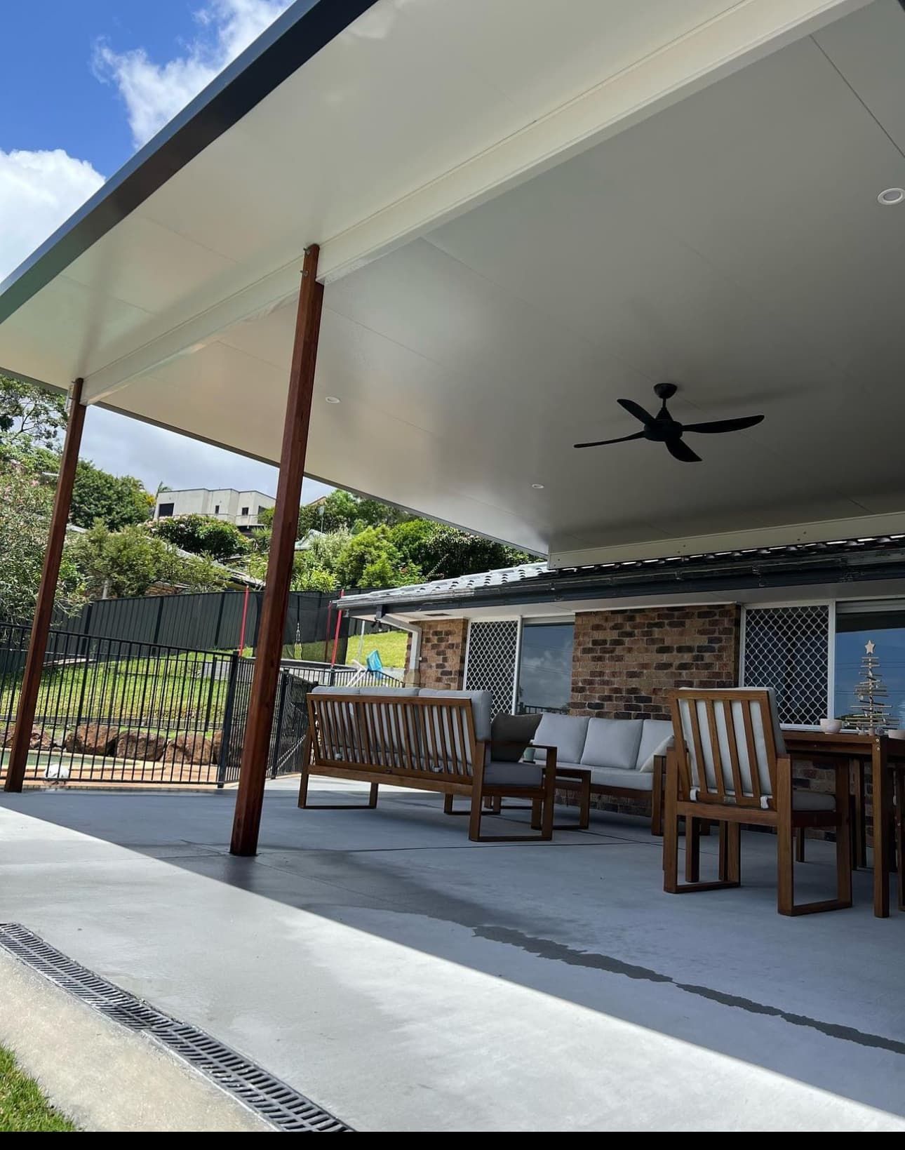 A Gold Coast patio with a ceiling fan and a couch and chairs under a canopy.