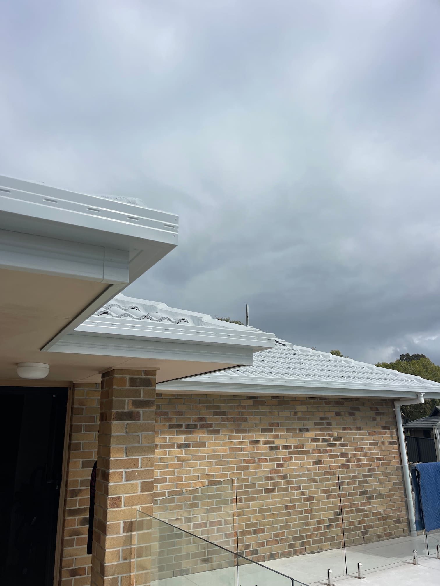 A brick Gold Coast house with a white roof and painted gutters.
