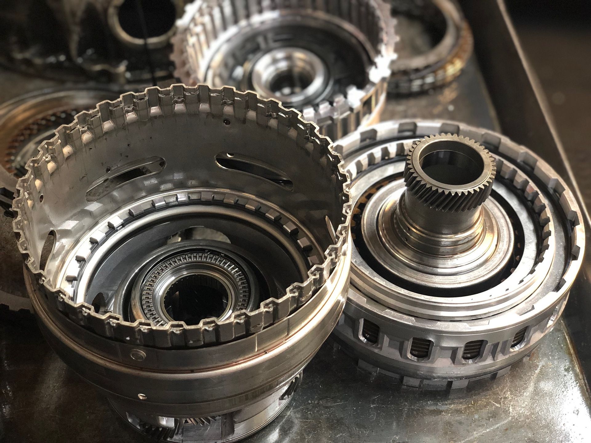 Disassembled metal transmission components on a metal tray, showcasing gears and housings.