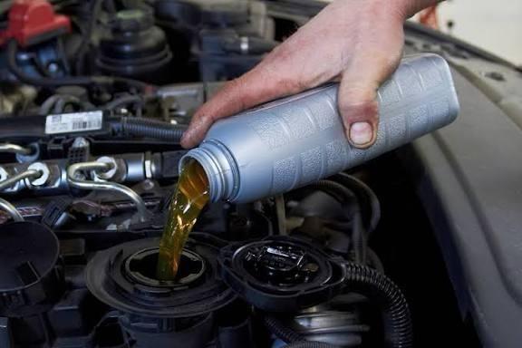 Hand pouring motor oil into a car engine.