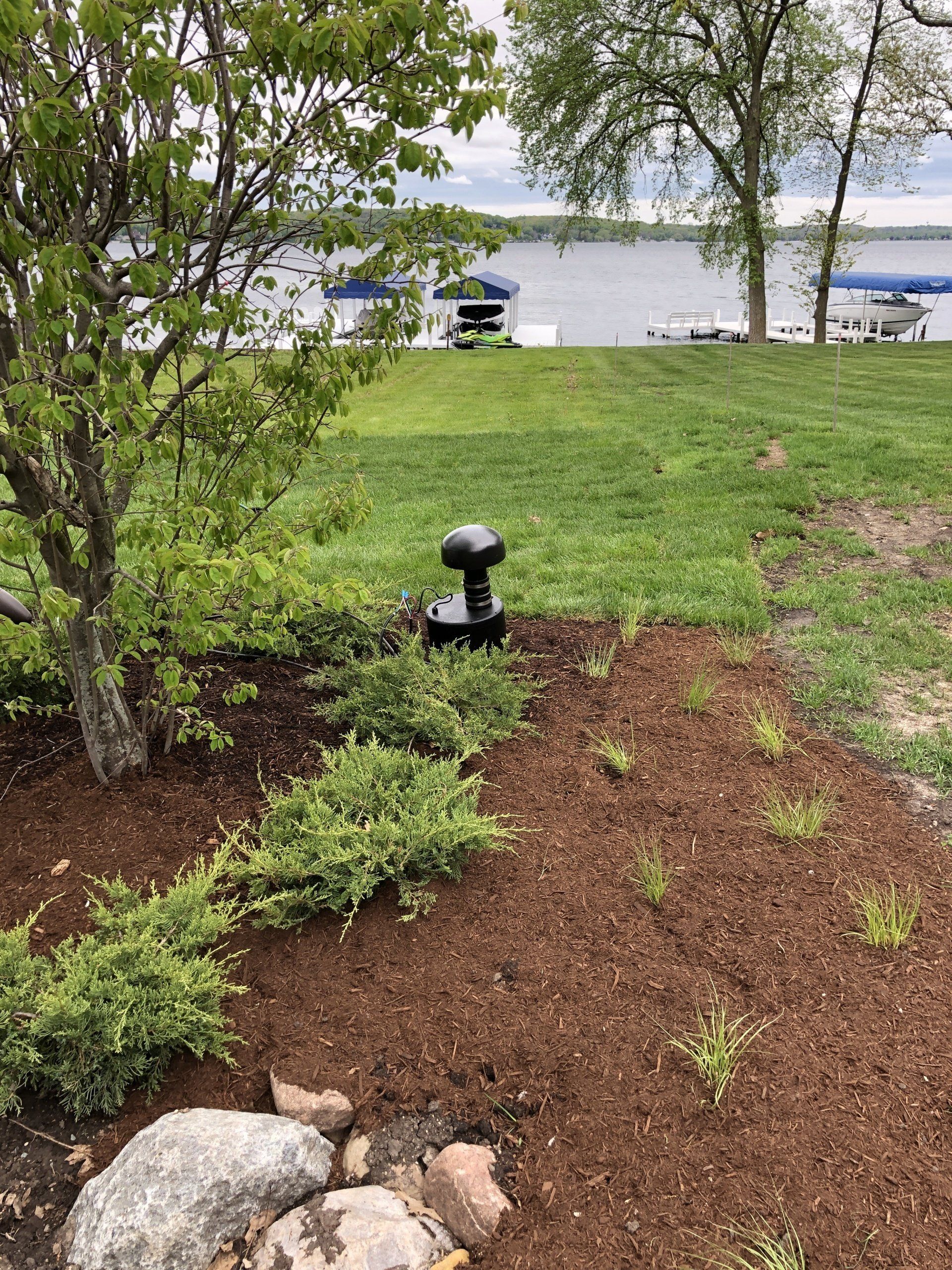 A speaker is sitting in the middle of a lush green field next to a body of water.