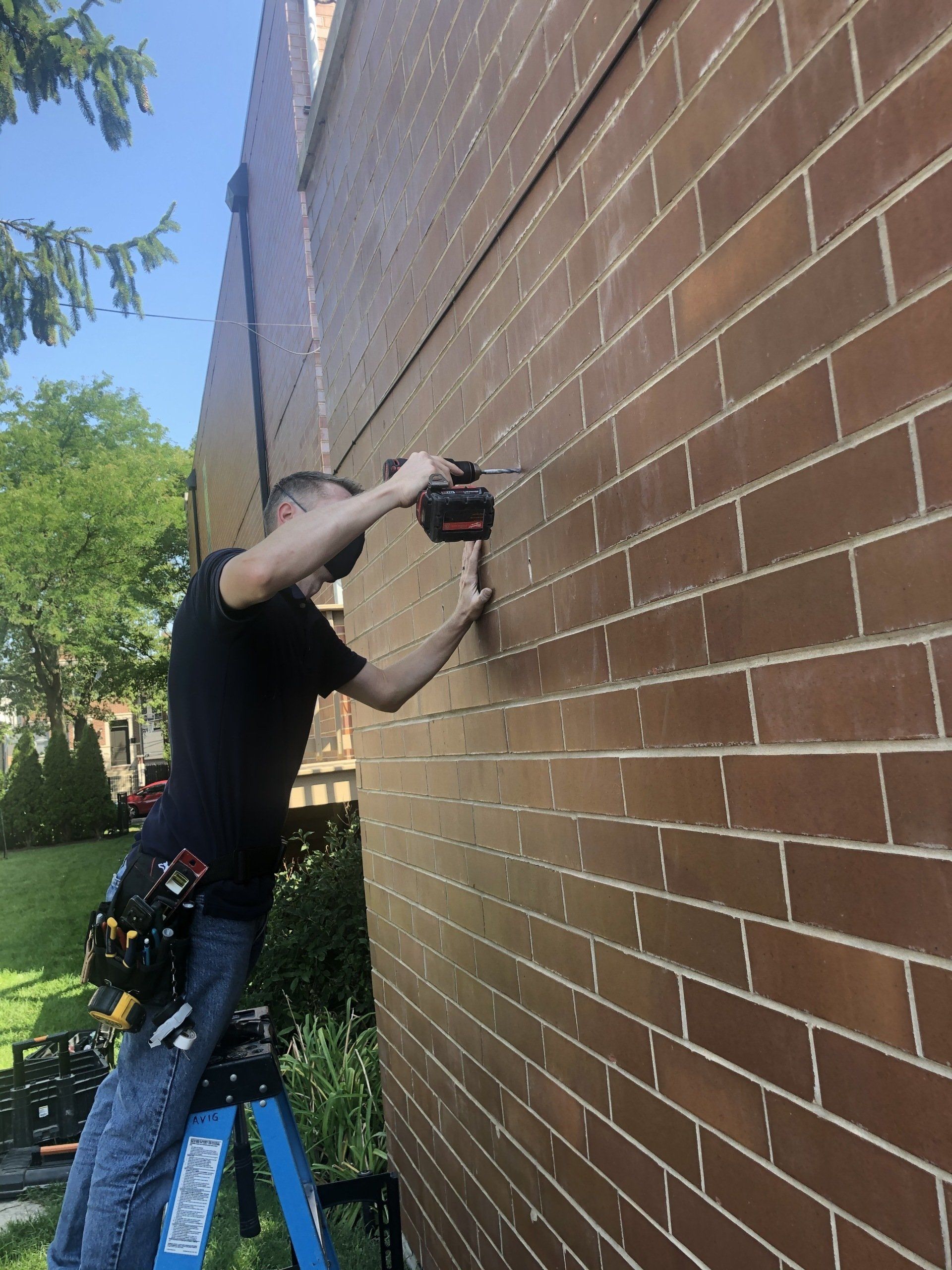 A man is working on a brick wall with a drill.