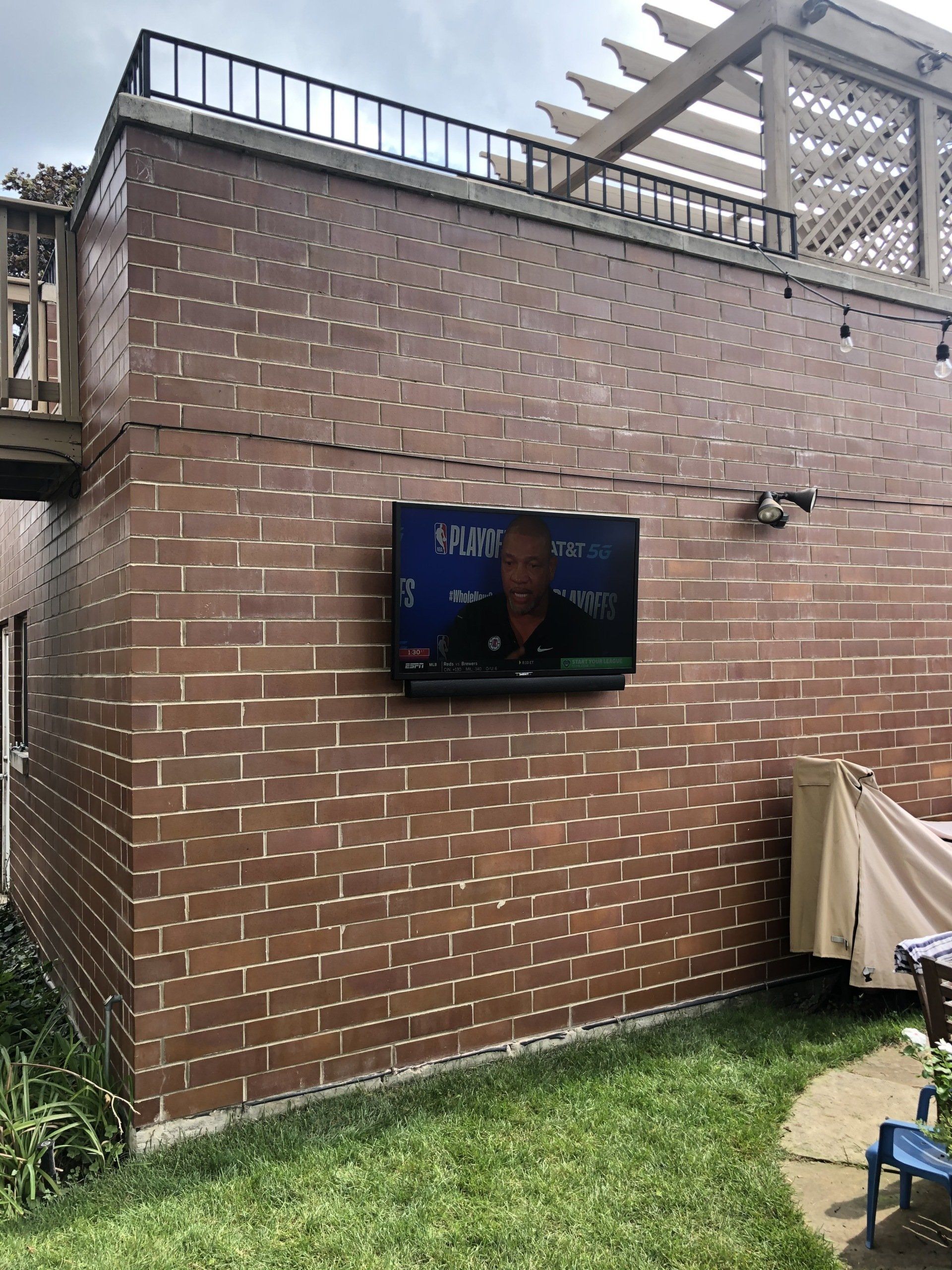 A television is mounted on the side of a brick building.