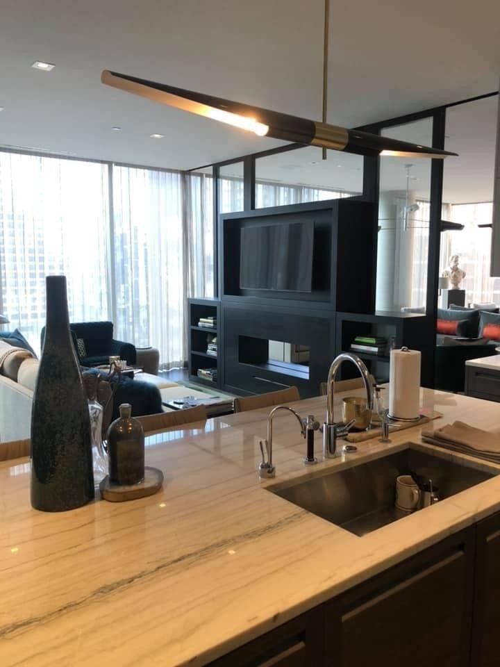 A kitchen with a sink and a television on the wall.
