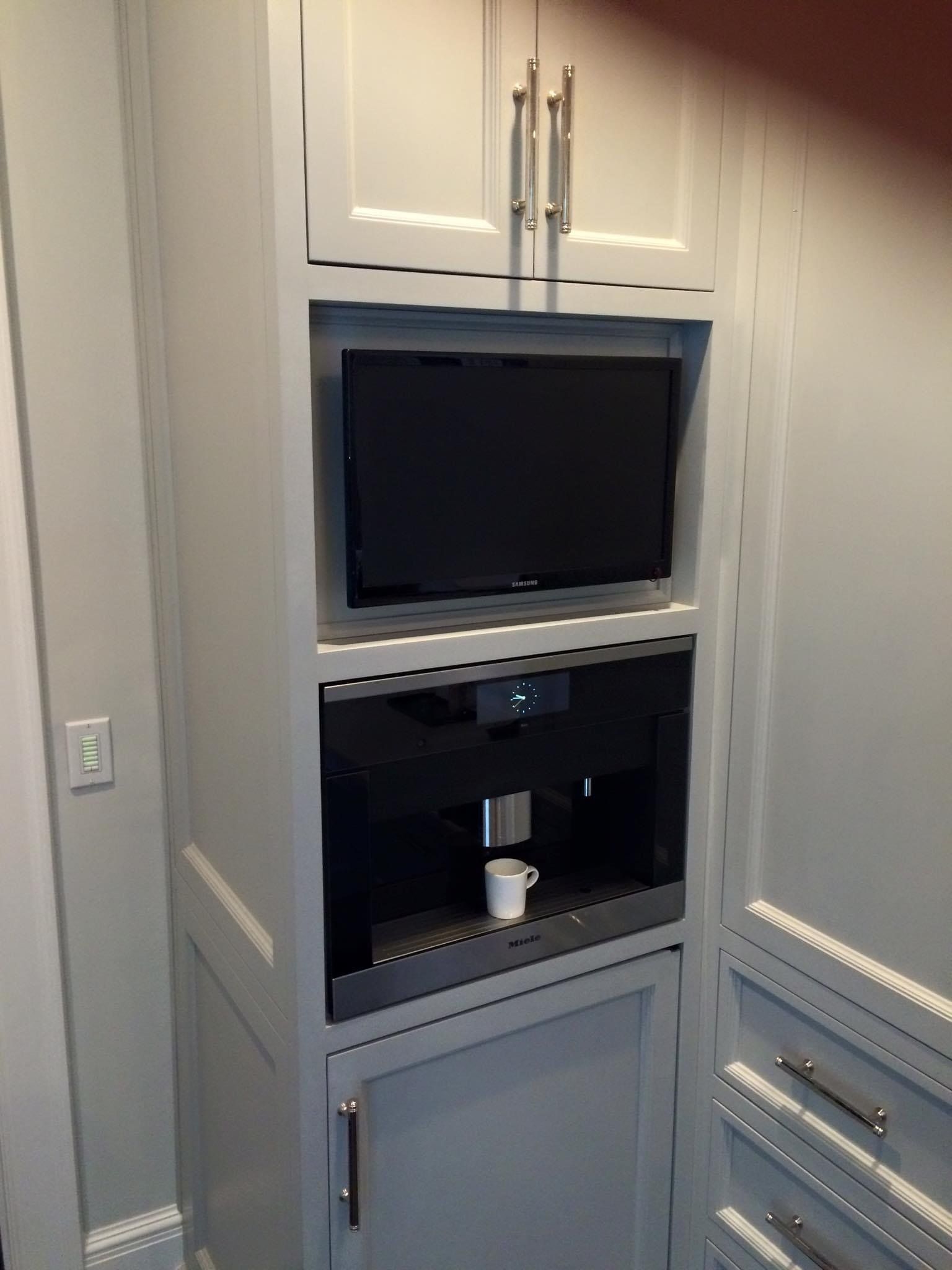 A kitchen with a coffee maker and a tv above it