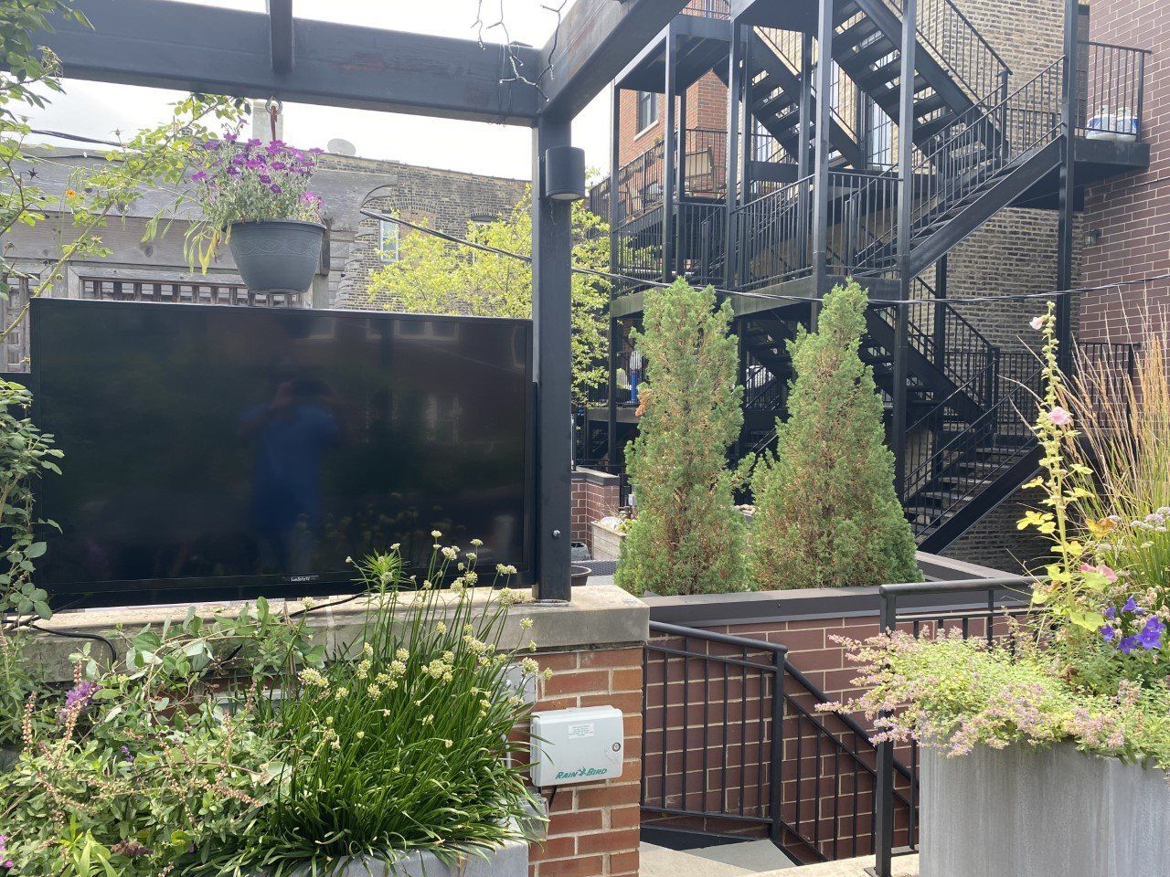 A large flat screen tv is sitting on the side of a building next to a fire escape.