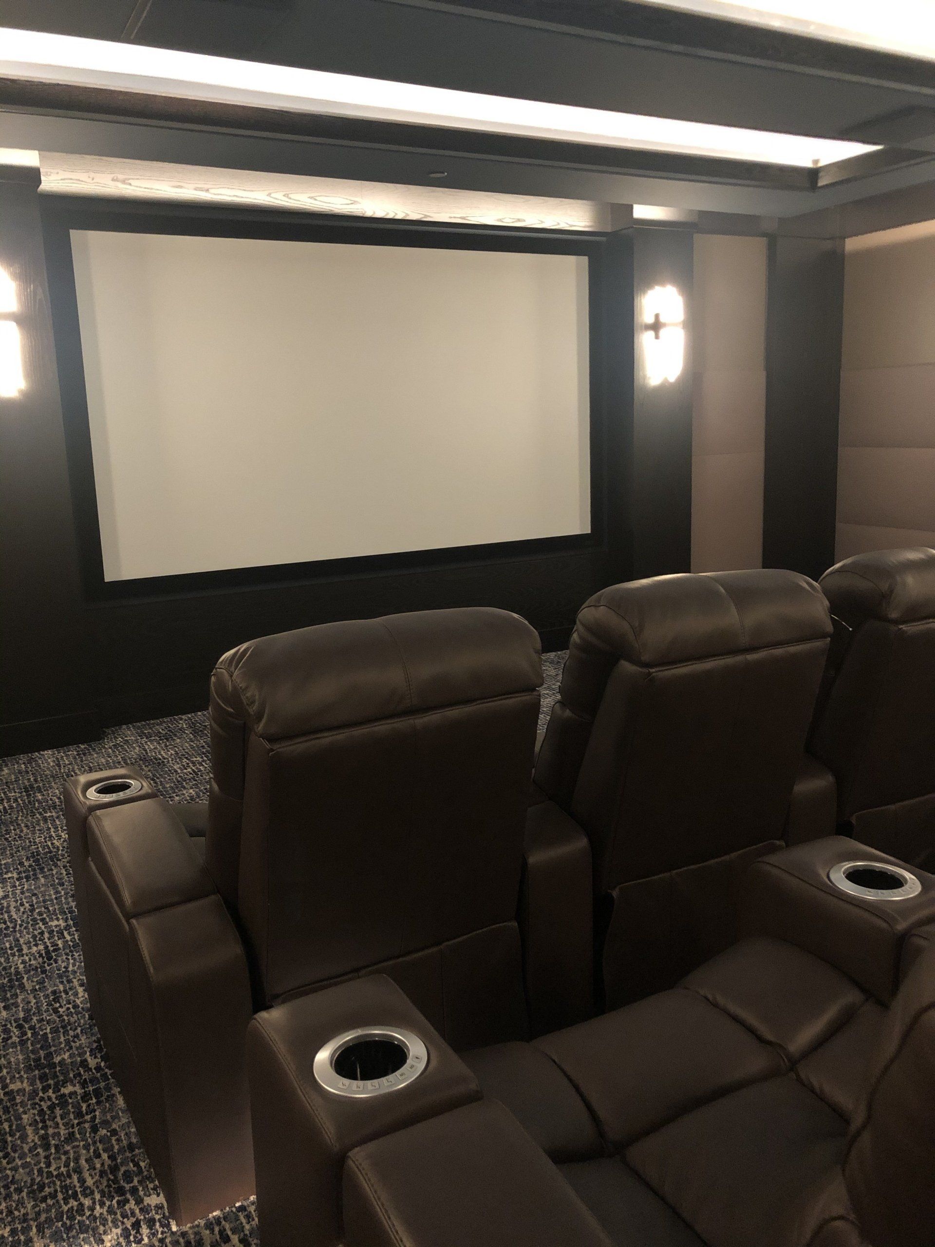 A home theater with a large screen and brown chairs