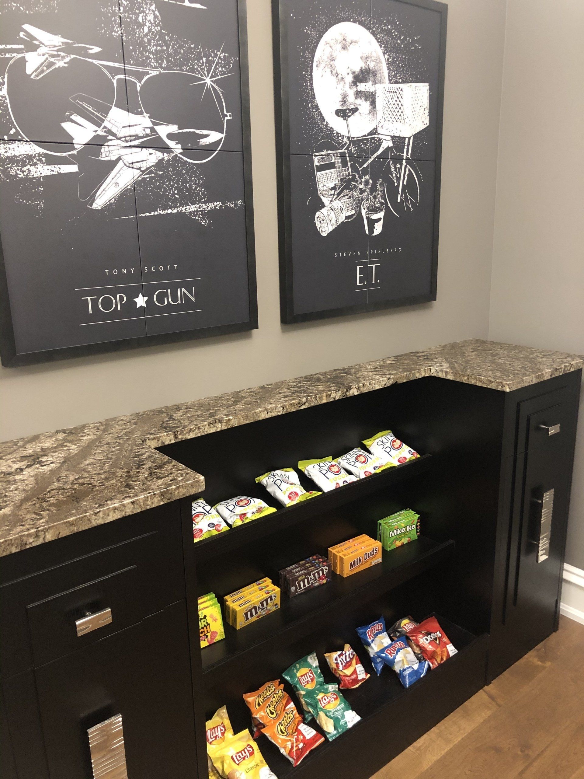 A room with a shelf filled with snacks and two posters on the wall.