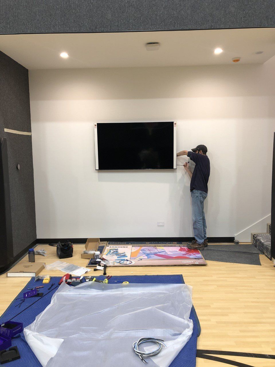 A man is installing a flat screen tv on a wall.