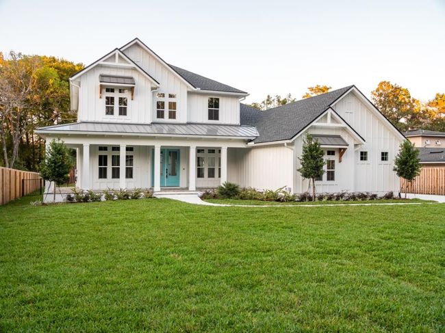 White farmhouse with teal front door and green lawn.