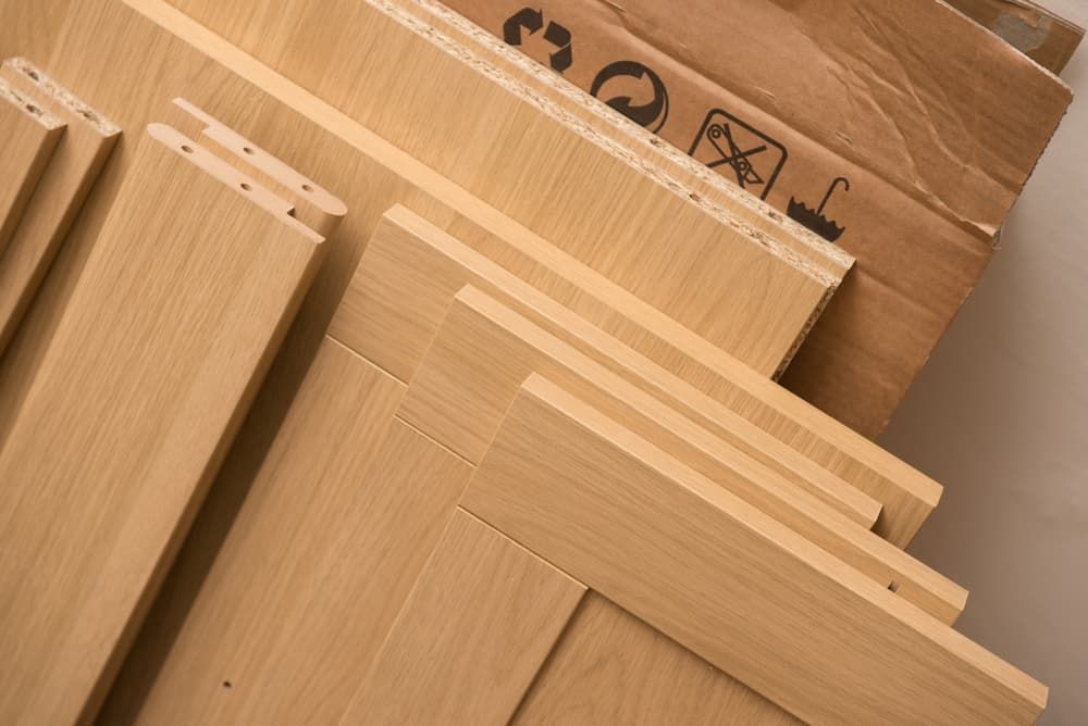 A pile of wood sits next to a cardboard box that says ' fragile ' on it— Alstonville Kitchens In Alstonville, NSW