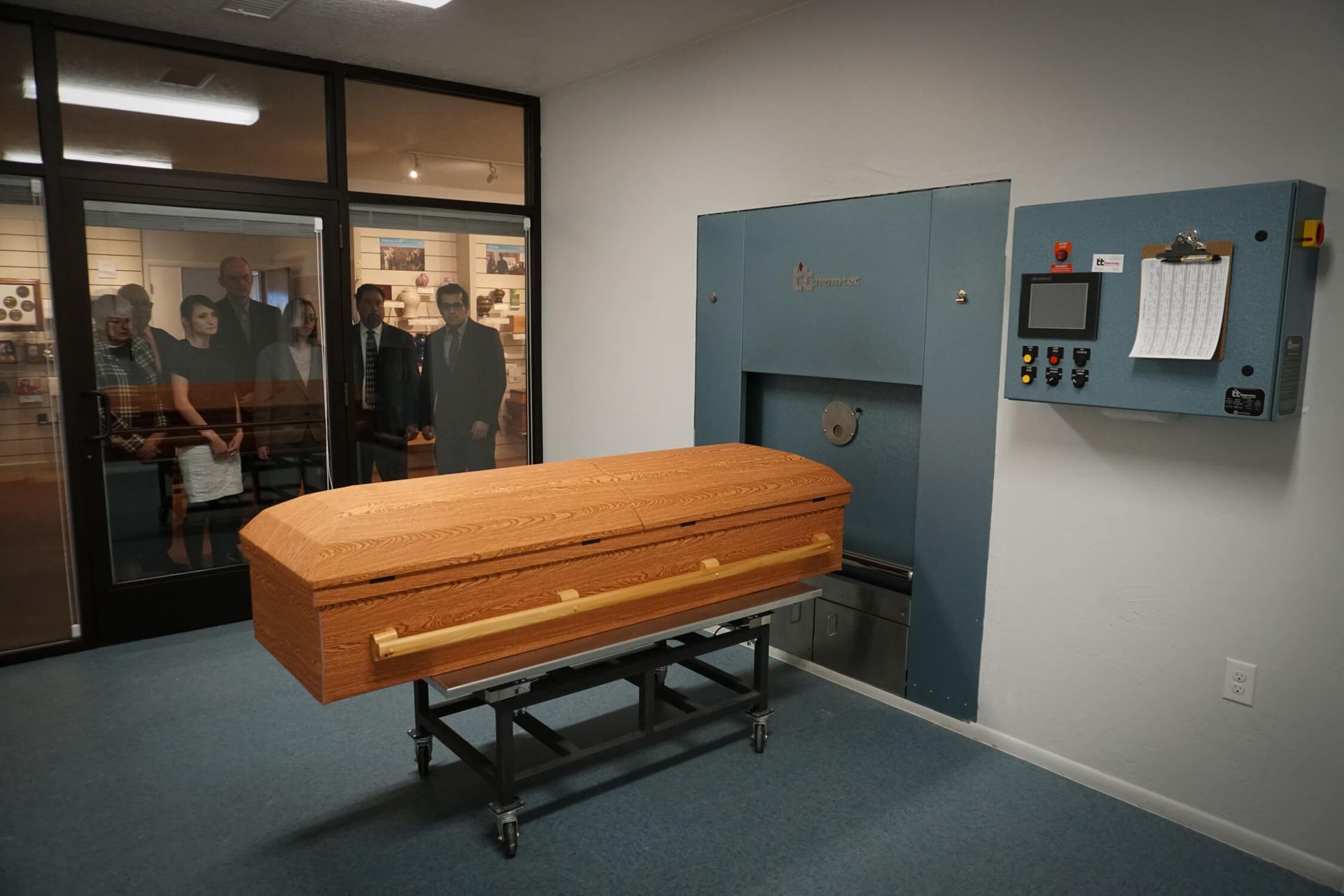 A large wooden coffin is sitting in a room next to a machine.