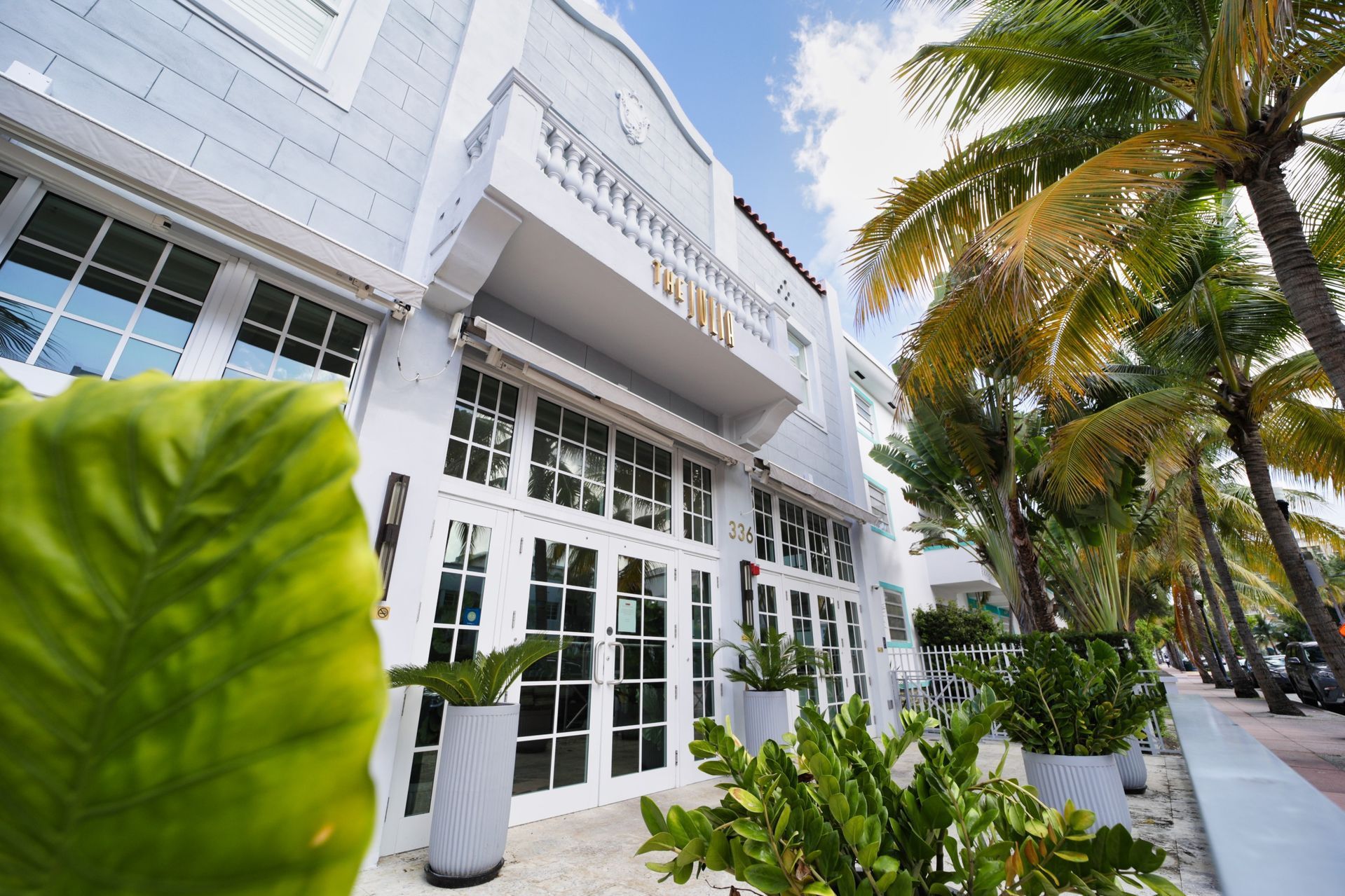 White building with French doors and palm trees in Miami.