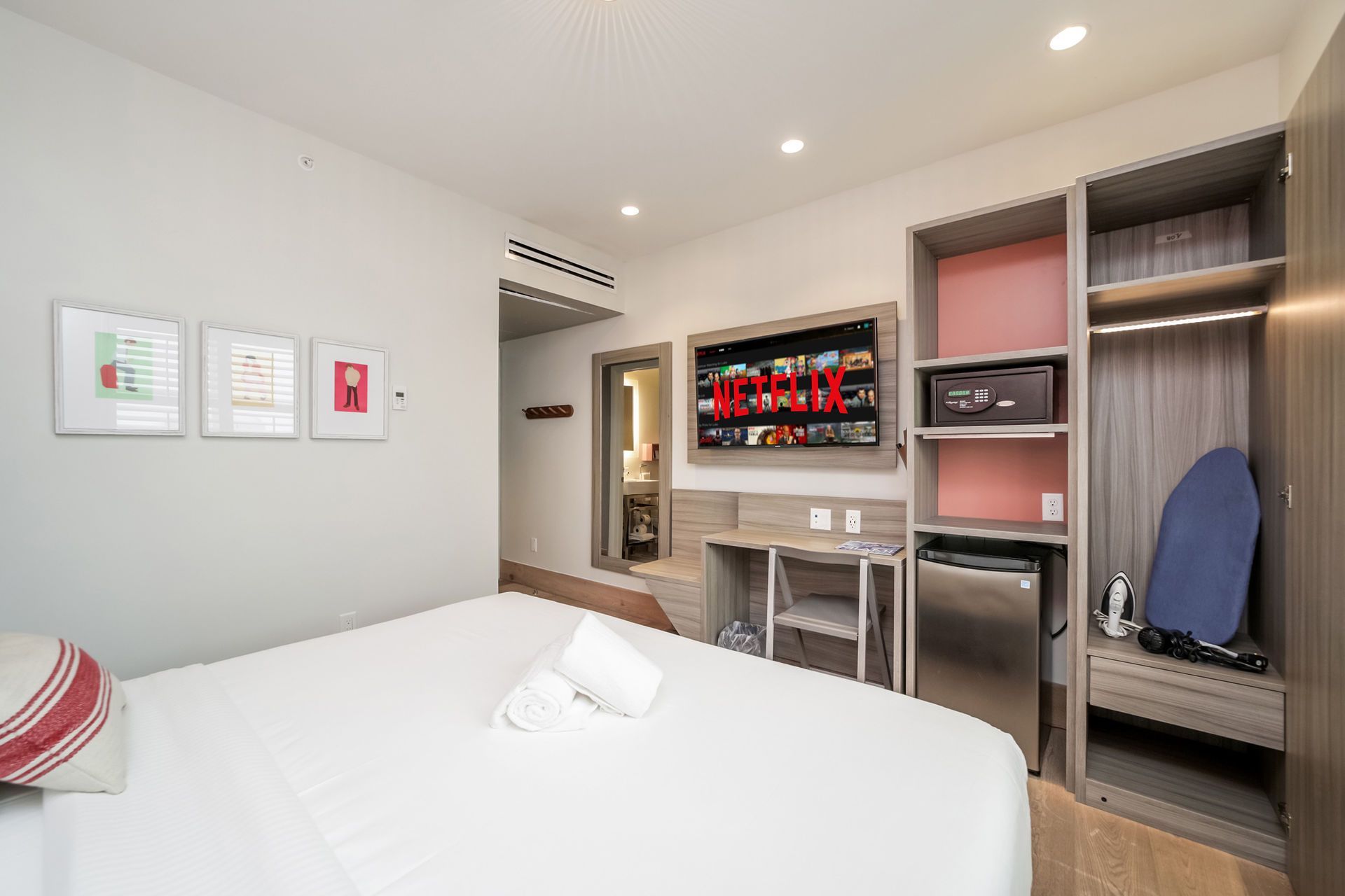 Hotel room with a bed, TV, closet, and small fridge.