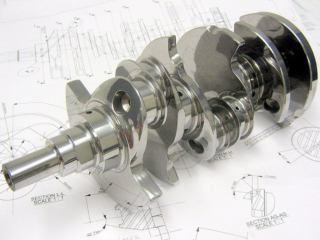 A metal crankshaft is sitting on top of a drawing