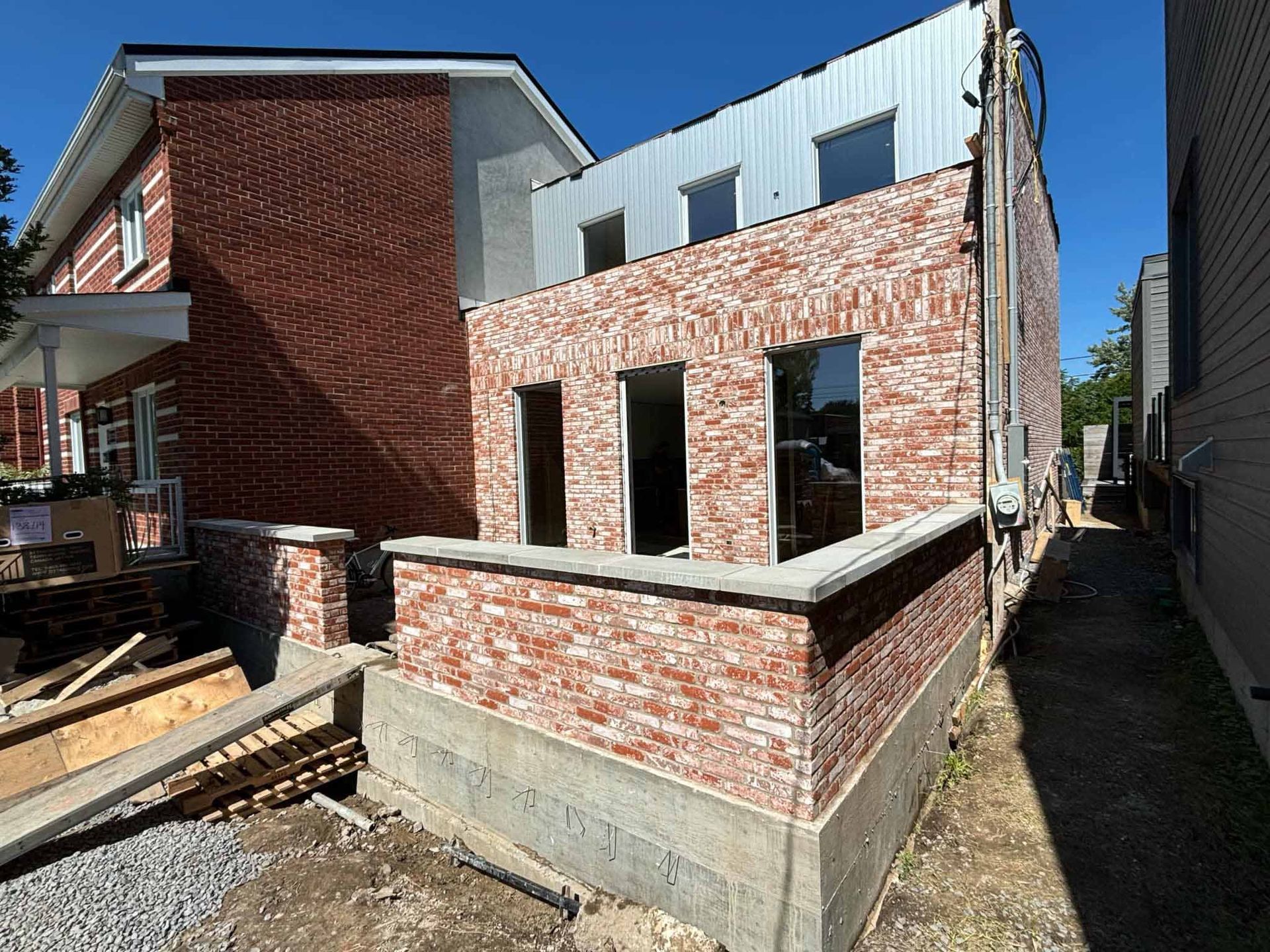 Vue extérieure d'un bâtiment en construction, avec des briques et des fenêtres neuves.