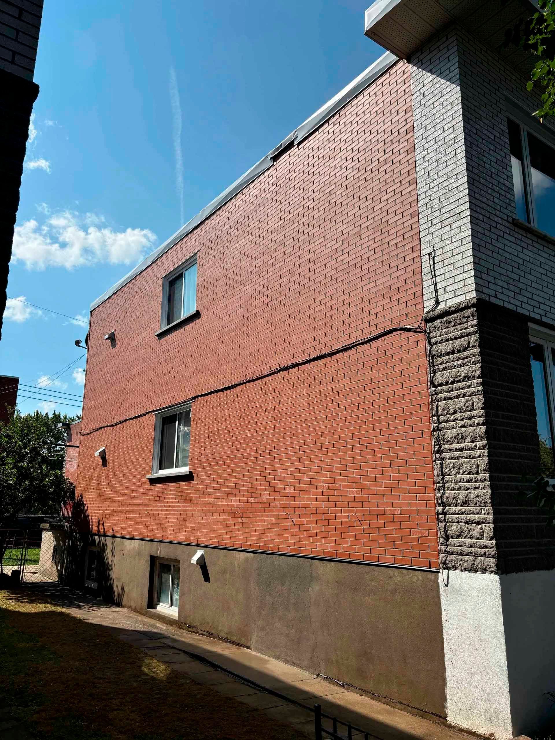 Façade d'un bâtiment en briques et en pierres par une journée ensoleillée.