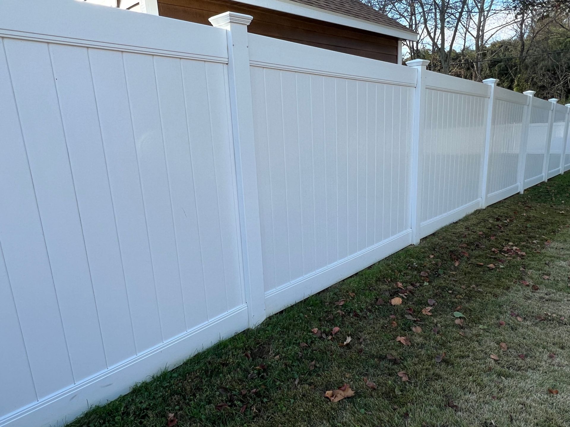 White vinyl privacy fence in a grassy yard.