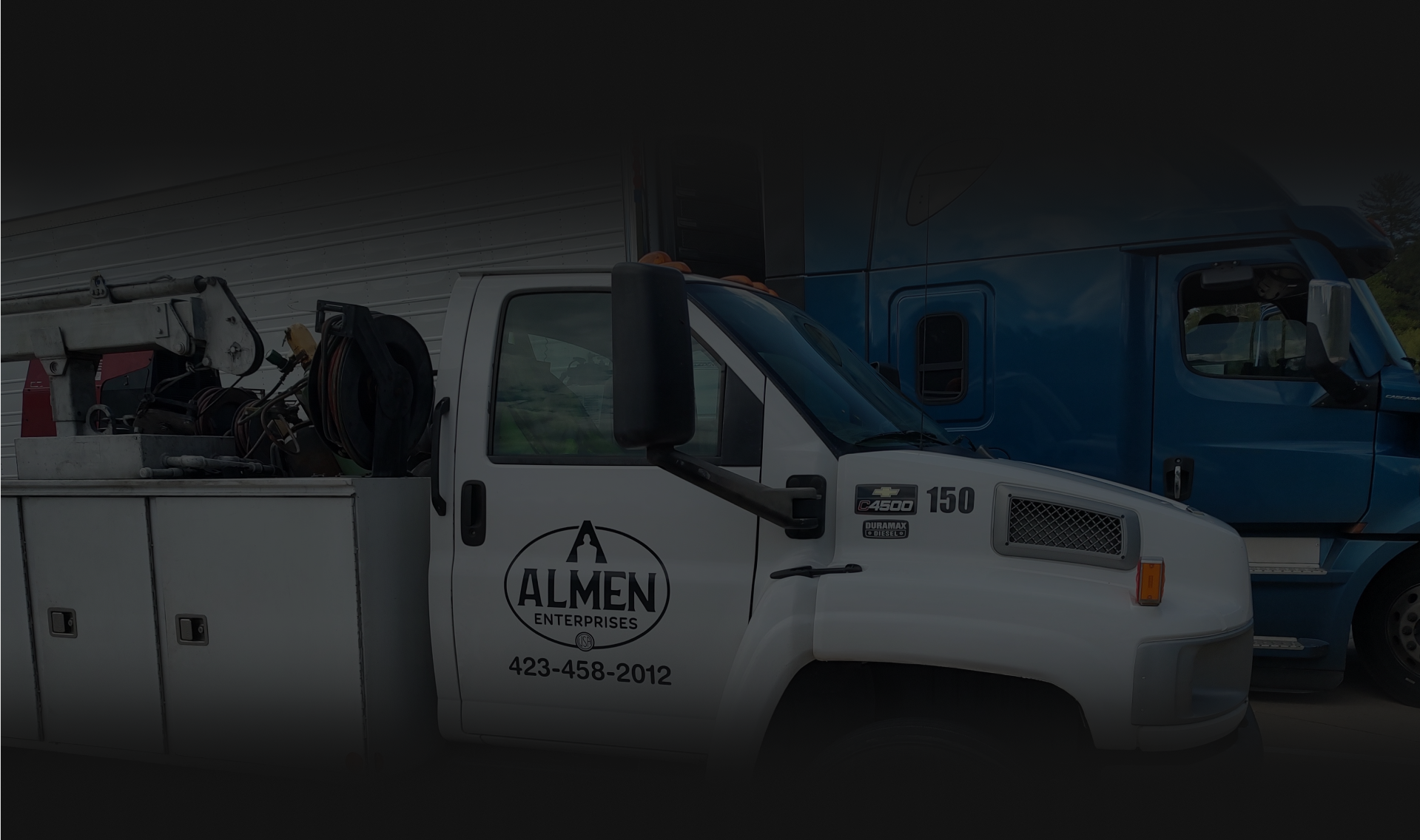 A row of semi trucks are parked in a parking lot - Almen Enterprises