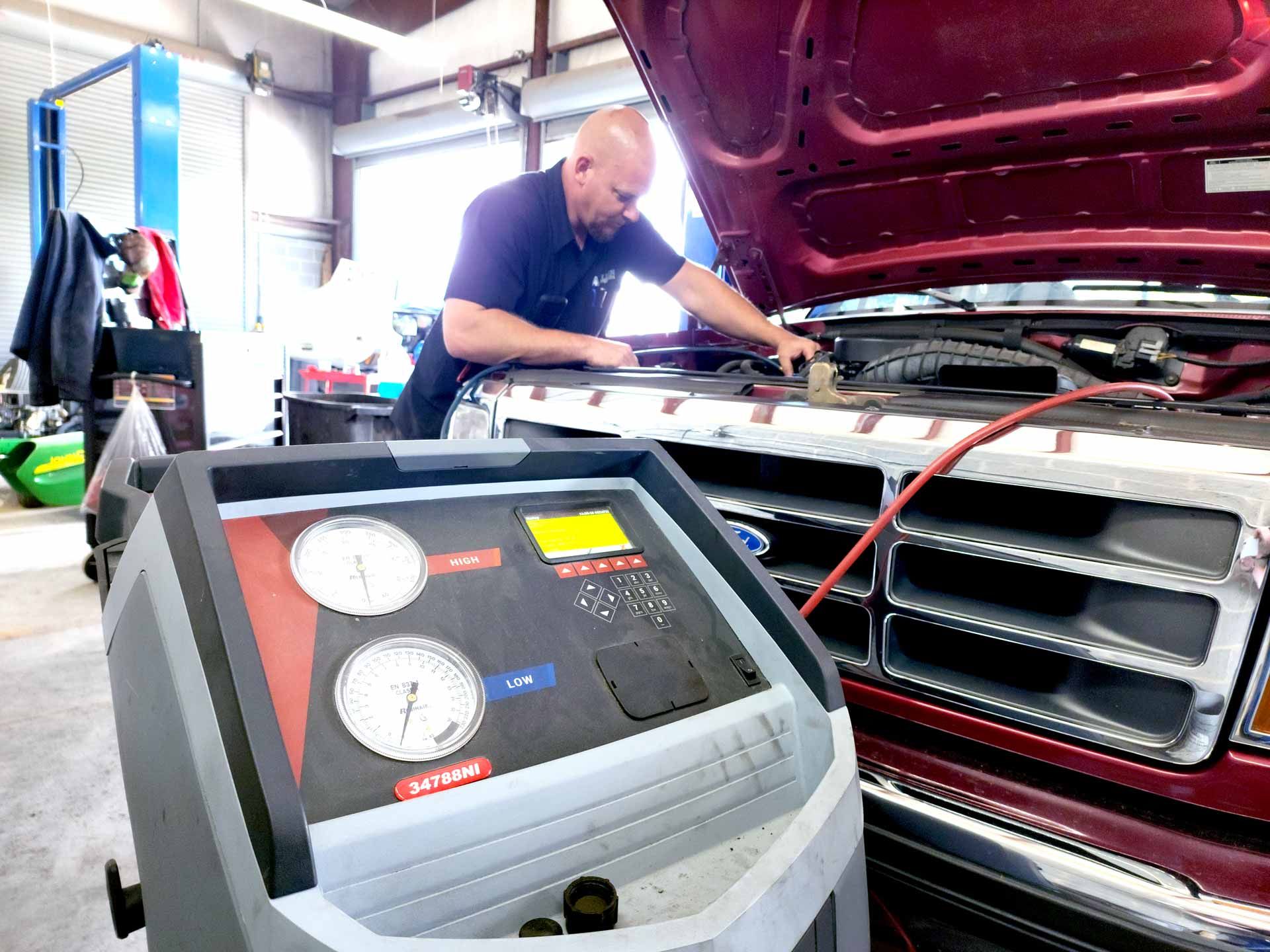 A man is working on a car with the hood open in a garage.