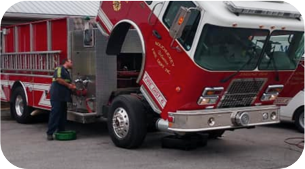 A man is working on a red fire truck with the hood up - Almen Enterprises