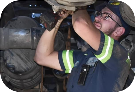 A man in a blue and green shirt is working under a vehicle - Almen Enterprises