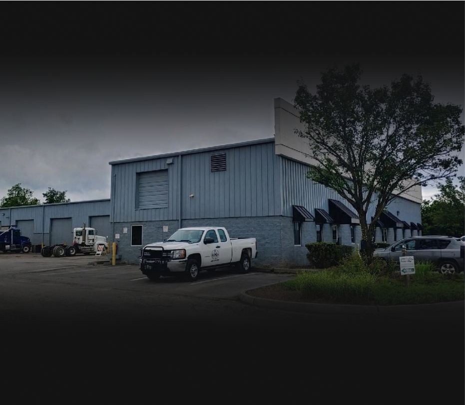 A white truck is sitting on a lift in a garage - Almen Enterprises