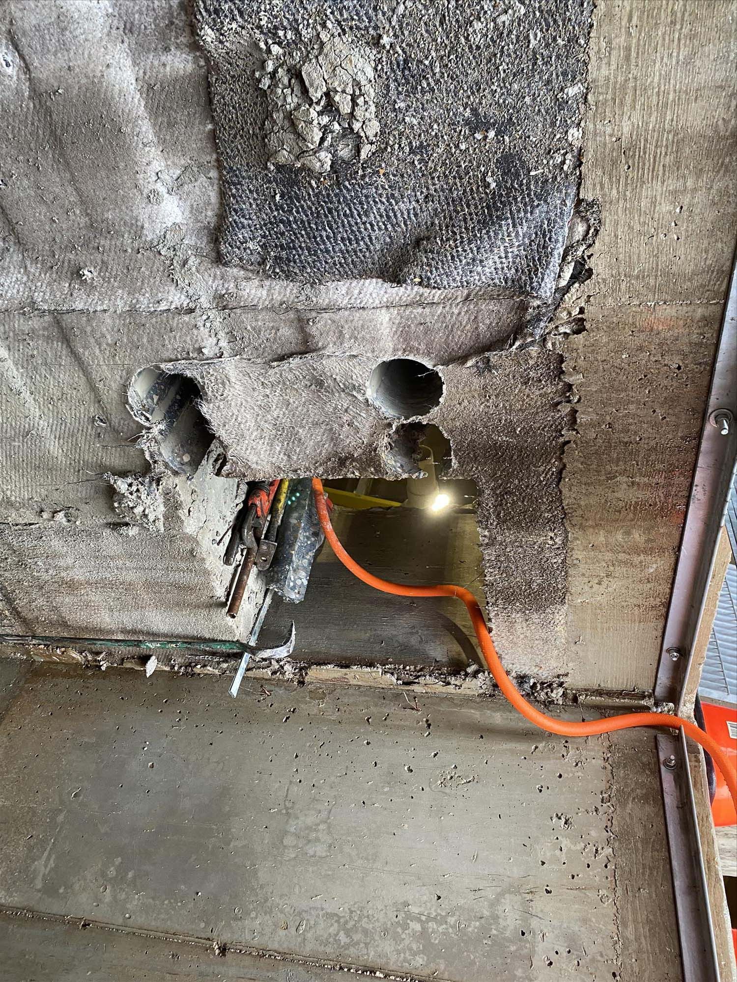 A concrete wall with a hole in it and a cord coming out of it.