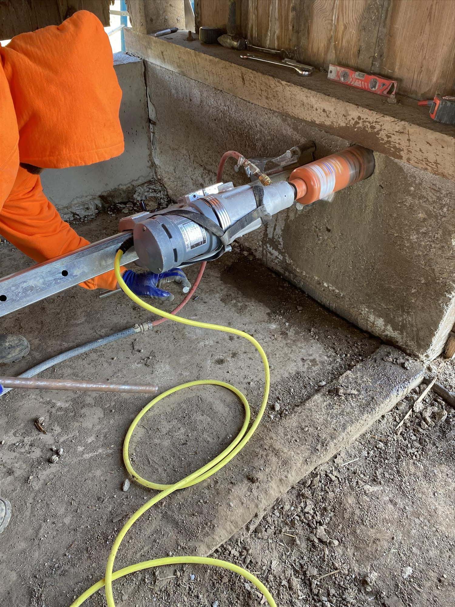 A person is using a machine to cut a hole in a concrete wall.