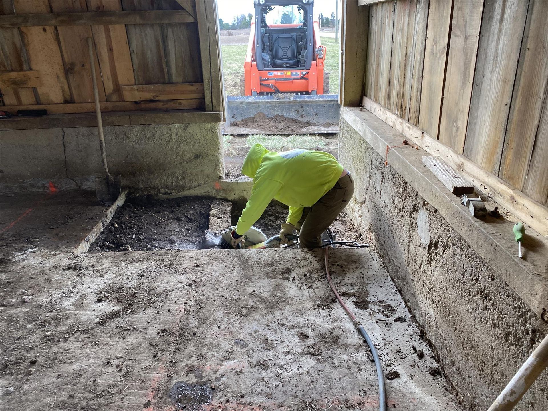 A man is kneeling down in a muddy area in front of a bulldozer.