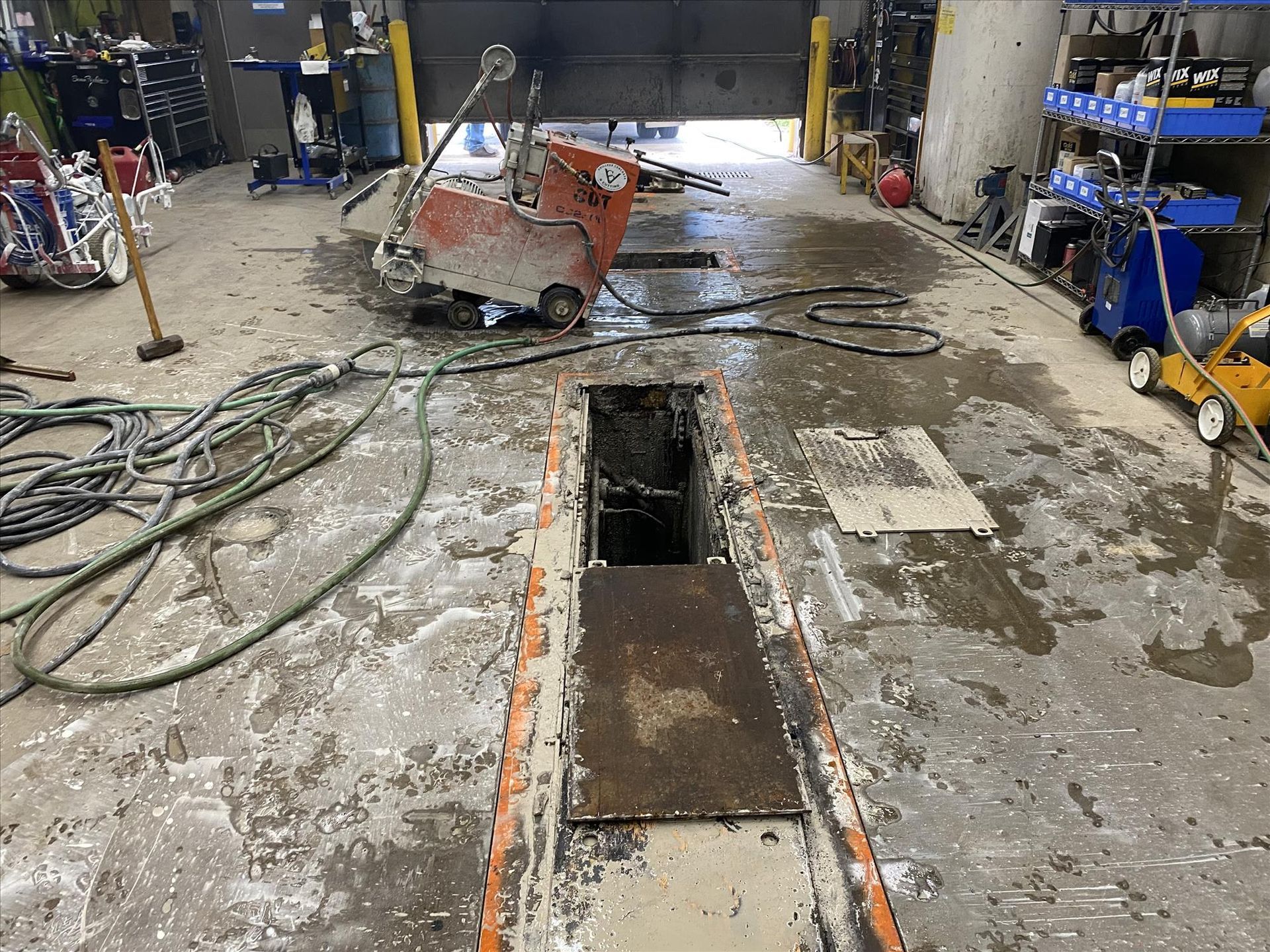 A concrete saw is cutting a hole in the floor of a garage.