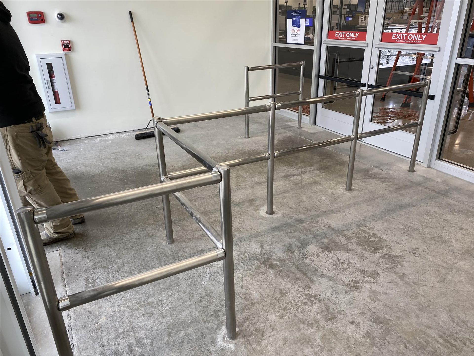 A man is standing next to a metal railing in front of a store.
