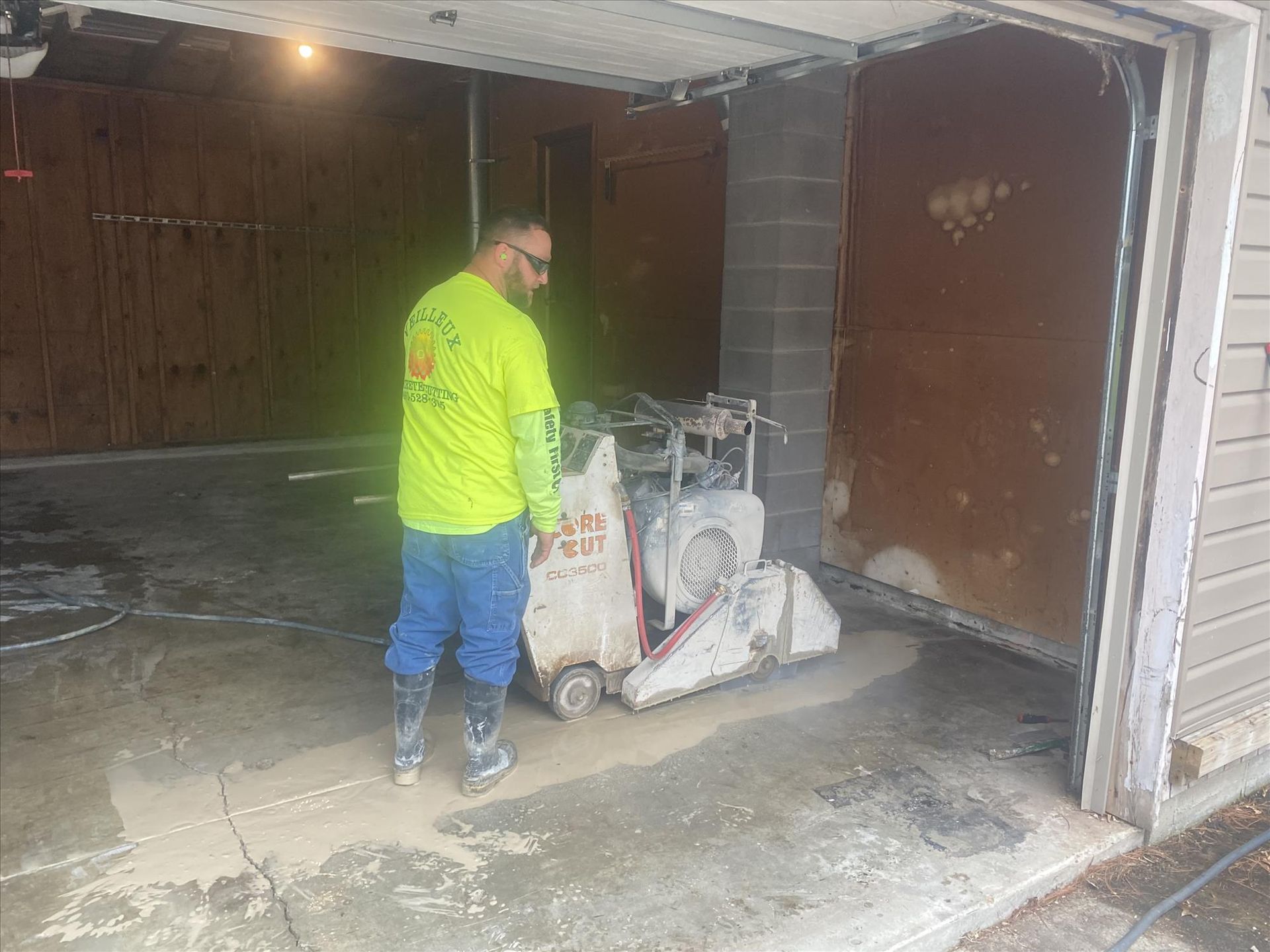 A man is cutting concrete in a garage with a machine.