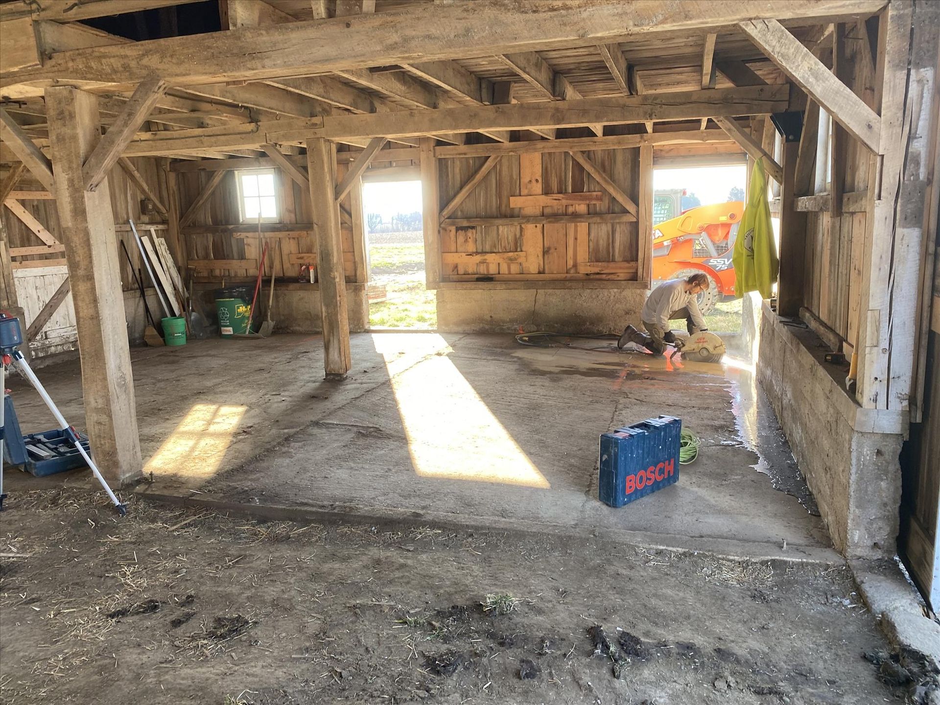 A man is standing inside of a wooden barn.