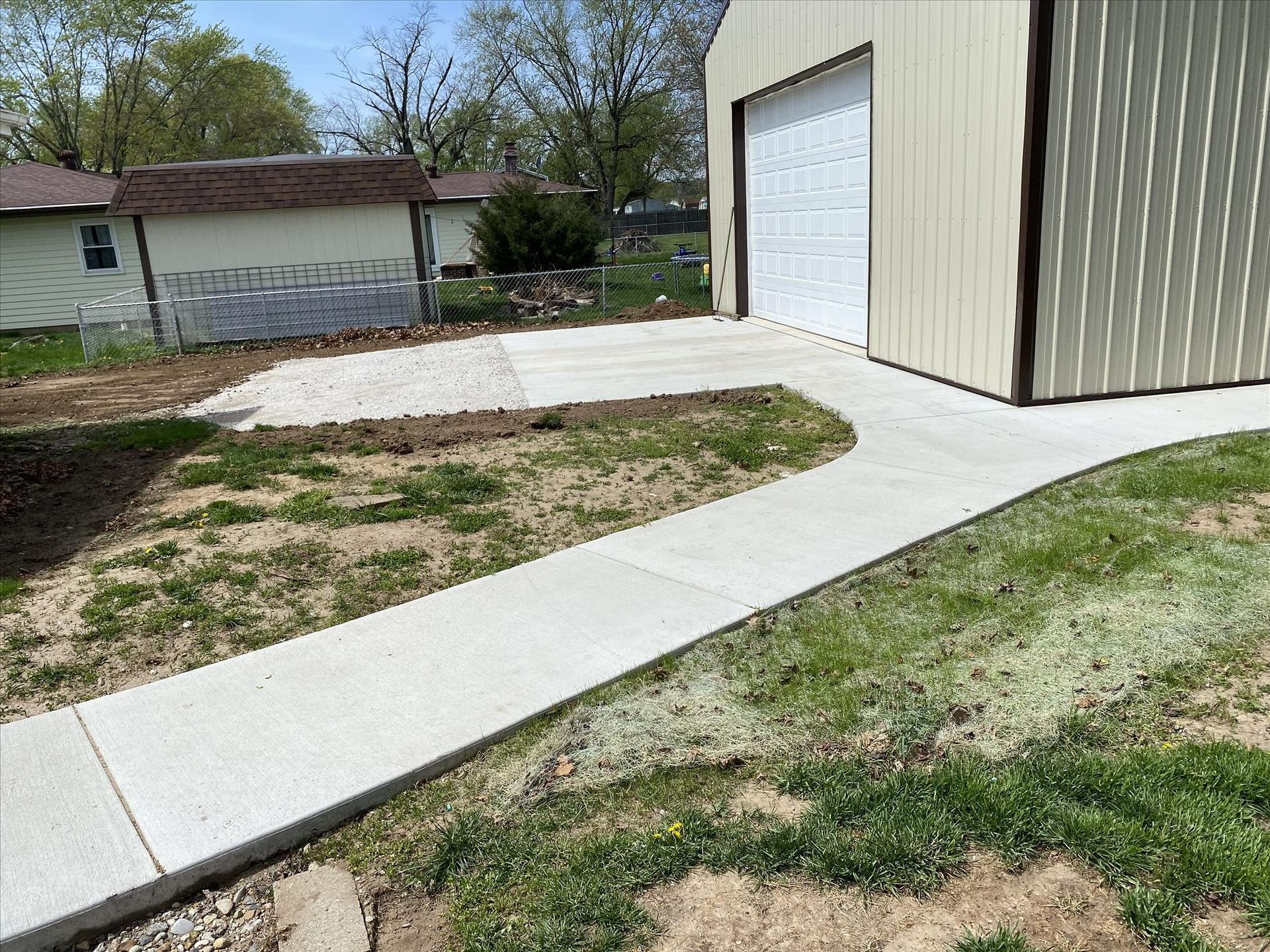 A concrete walkway leading to a garage with a white garage door.