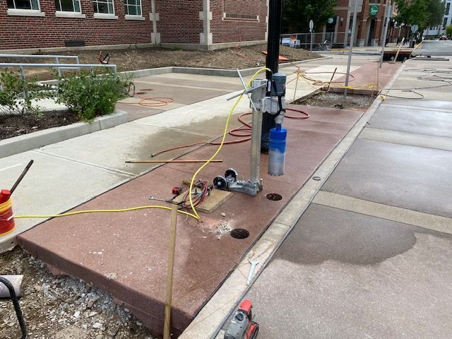 A machine is being used to cut concrete on a sidewalk.