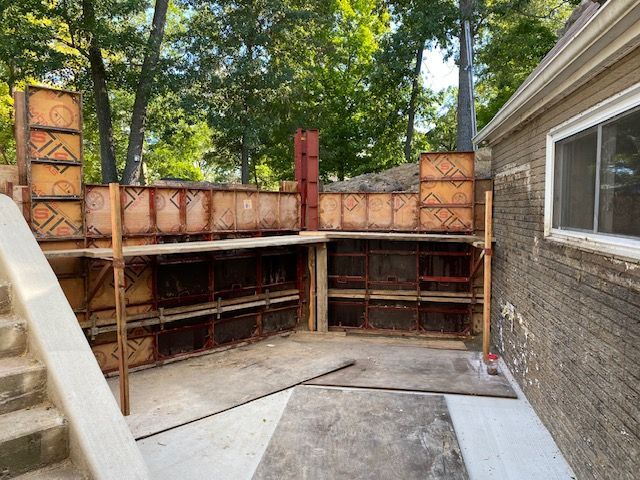 A concrete wall is being built in the backyard of a house.