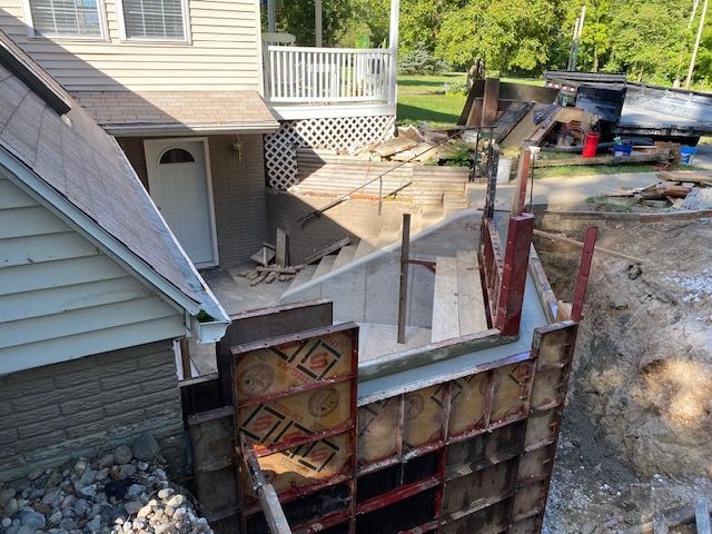A house is being remodeled and a concrete wall is being built in front of it.