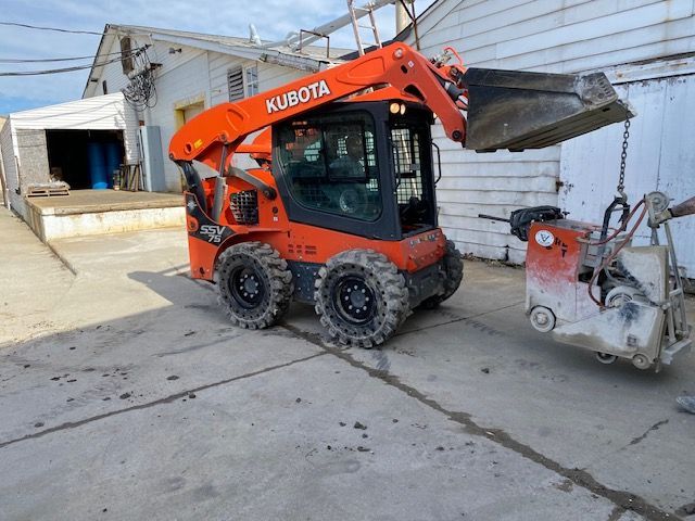 A kubota skid steer is parked next to a concrete saw.
